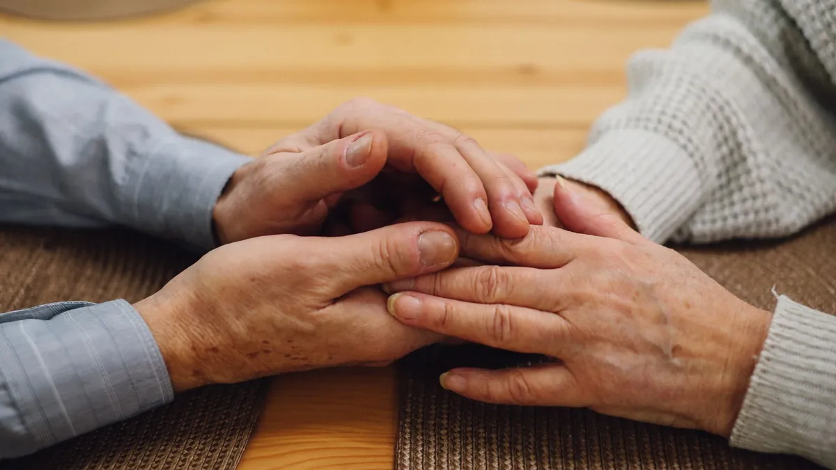 A caregiver holding the hand of an elderly person