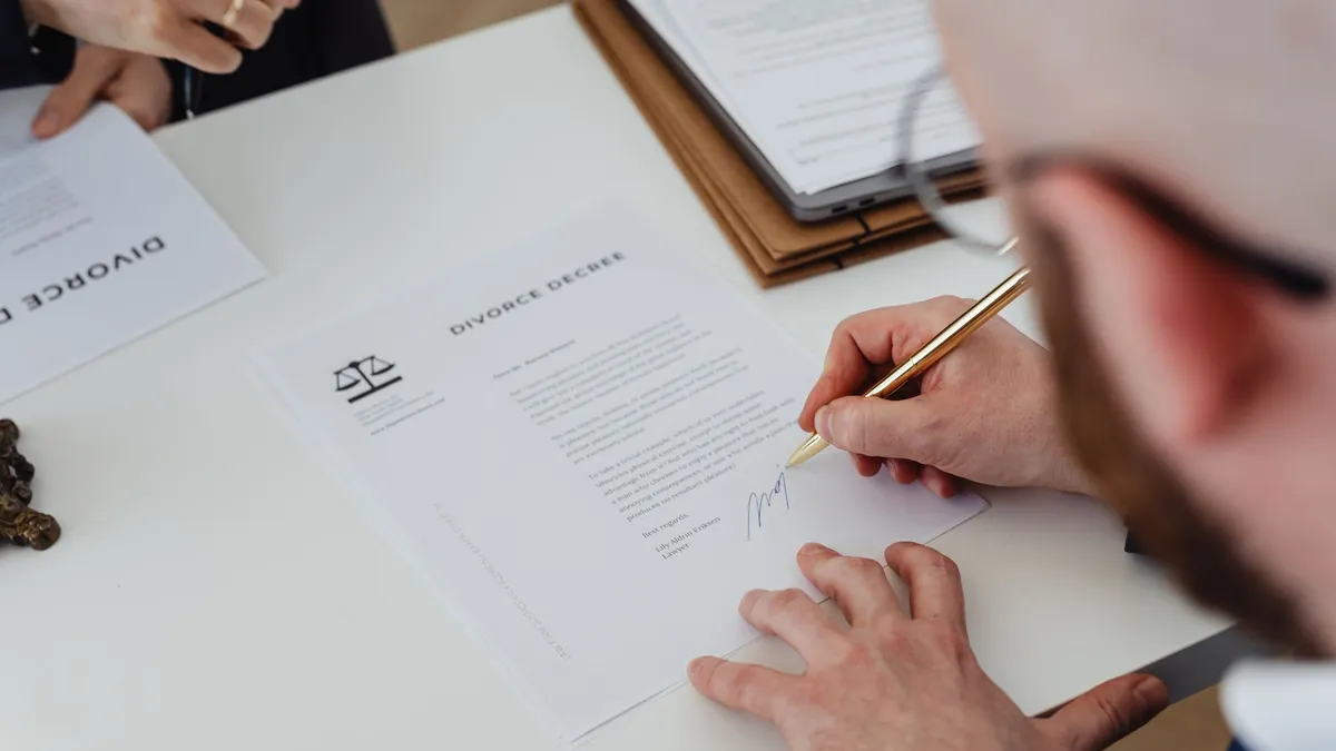 A person signing a document with a pen